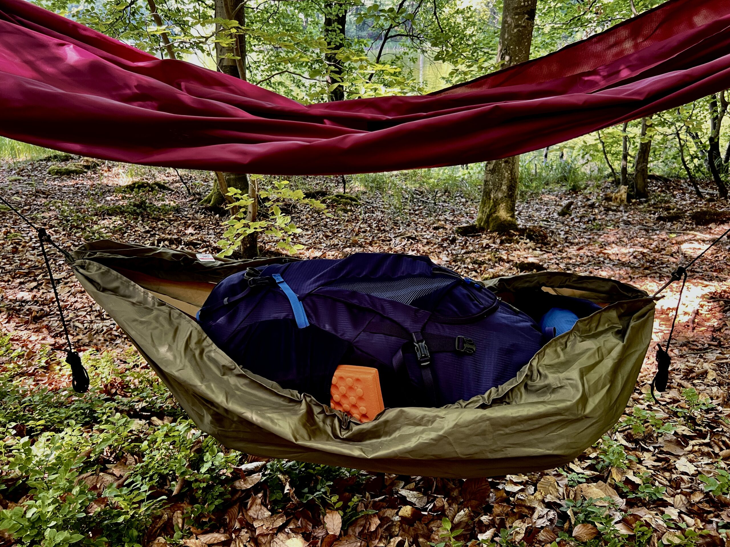 Bagażówka wisząca pod hamakiem. Zbliżenie na bagażówkę. Produkt marki WYDRA 13. W mini hamaku znajduje się duży, turystyczny plecak.