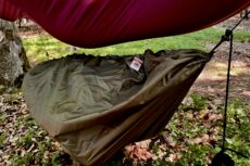 Bagażówka wisząca pod hamakiem. Zbliżenie na bagażówkę. Produkt marki WYDRA 13. W mini hamaku znajduje się duży, turystyczny plecak.